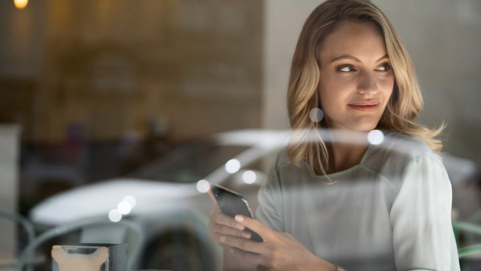 Femme regardant Hyundai Ioniq par la fenêtre en souriant.