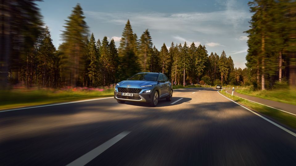 KONA Hybrid roulant sur une route de campagne ensoleillée.